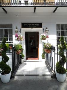 倫敦的住宿－避風港酒店，门前有盆栽植物的酒店入口