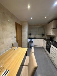 - une cuisine avec une table en bois et des placards blancs dans l'établissement Luxury Flat, à Londres