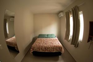 Dormitorio pequeño con cama y espejo en 3- AKAHAI -Aloha Bratz Apartments, en Palhoça