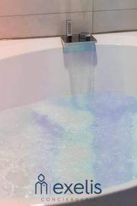 una bañera llena de agua azul en una habitación en Cure d'Air en amoureux, en Nancy
