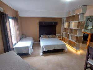 1 dormitorio con 2 camas y estante para libros en departamentos lasserre, en Río Grande