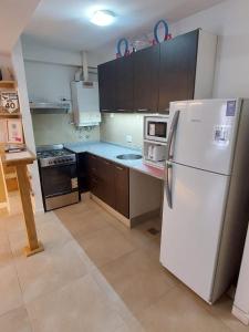 Una cocina con un refrigerador blanco y una estufa. en departamentos lasserre, en Río Grande 5 fotos más