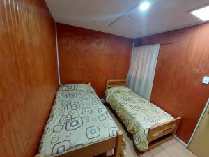 Habitación pequeña con 2 camas y paredes de madera. en Residencial RO, en Copiapó