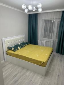 um quarto com uma cama com lençóis amarelos e uma janela em Apartment in street Toktogula 77 em Bishkek