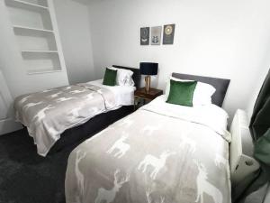 a bedroom with two beds with green and white sheets at 4Bed House MK in Simpson
