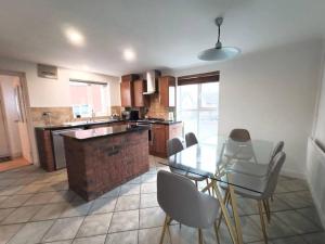 a kitchen with a glass table and chairs and a counter at 4Bed House MK in Simpson