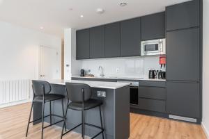 a kitchen with black cabinets and two bar stools at Grange Two in Dublin