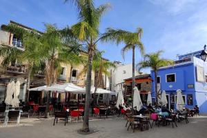 une cour avec des tables, des chaises et des palmiers dans l'établissement Romantico Apartamento en el Puerto de Denia, à Dénia