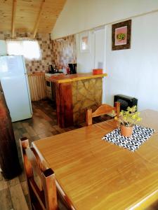cocina con mesa de madera y nevera en Cabañas Epuyen en Trevelín