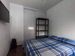 ein kleines Schlafzimmer mit einem Bett und einem TV in der Unterkunft Hermoso y acogedor departamento Colinas Santiago in Manzanillo