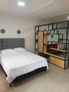 a bedroom with a large white bed and a shelf at HERMOSO APTO LA ESTRELLA in La Estrella