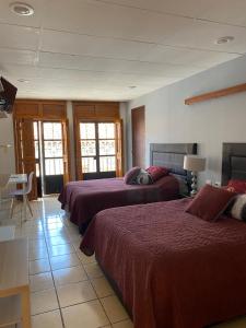 una camera d'albergo con tre letti con coperte rosse di Posada Catalina a Zacatlán