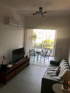 a living room with a couch and a tv and a table at Ubatuba Apto Encantador in Ubatuba