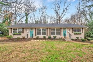 a white house with blue doors and a yard at Homey 2BR Condo—King Bed—Lovely Location & Parking in Charlotte