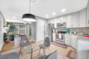 a kitchen with white cabinets and a glass table and chairs at Homey 2BR Condo—King Bed—Lovely Location & Parking in Charlotte