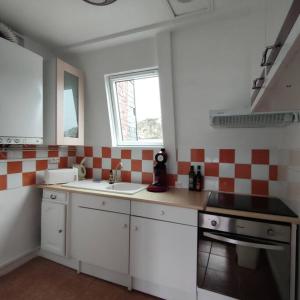 - une cuisine avec du carrelage rouge et blanc sur le mur dans l'établissement L'Arche, appartement sur les toits d'Etretat, à Étretat