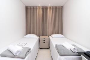 twee bedden in een kamer met witte muren bij Aptos modernos no Jardim Goiás FRP in Goiânia