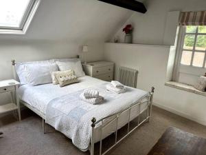 1 dormitorio con 1 cama con sábanas y almohadas blancas en The Old Barn Throop. Spacious Barn conversion., en Bournemouth
