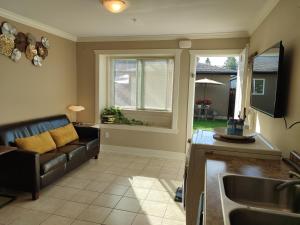 a kitchen and living room with a couch and a sink at Private Suite w King Bed, Ground Level, Naturally Bright in Vancouver