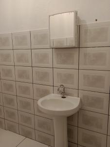 Baño blanco con lavabo y espejo en Pousada Acalanto, en Pirenópolis