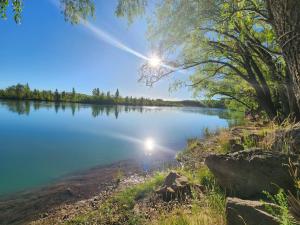 a view of a lake with the sun shining at Luz de Luna in Plottier