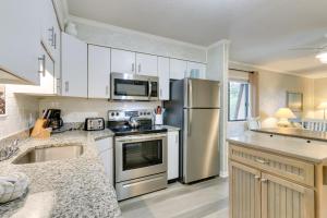 a kitchen with white cabinets and a stainless steel refrigerator at Hilton Head Condo with Balcony and Pool, Walk to Beach in Hilton Head Island