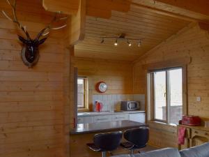 a kitchen in a log cabin with a counter and stools at Baytree Lodge - Uk13322 in Melbourne