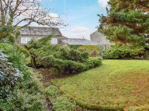 un jardín con una casa y un árbol en The Bothy en Old Hutton