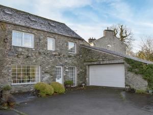 a brick house with a white garage and a driveway at The Bothy in Old Hutton