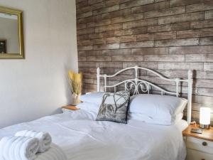 - une chambre avec un lit blanc et un mur en briques dans l'établissement The Farmhouse, à Benllech