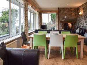 a dining room with a table and green chairs at Janvalyn in Tregarth