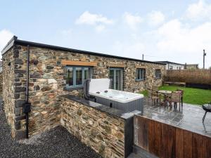 a stone cottage with a hot tub on a patio at Primrose Cottage in Holyhead
