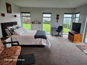a bedroom with a bed and a flat screen tv at House on the Hill in New Plymouth