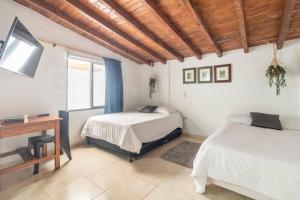 a bedroom with two beds and a desk and a television at Letto Hostal in Rionegro