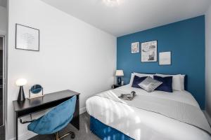 Schlafzimmer mit blauen Wänden und einem Bett mit einem Schreibtisch in der Unterkunft Cosy 4-Bedroom Apartment next to Borough in London