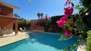 a swimming pool in a yard with pink flowers at Studio with Private Swimming Pool and Garden in Cascais