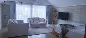 sala de estar con 2 sillas y TV de pantalla plana en Bombua Beach House en Luganville