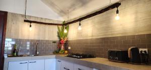 a kitchen with white cabinets and a stove and lights at Bombua Beach House in Luganville