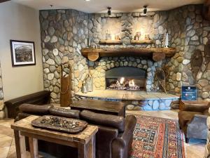 a stone fireplace in a living room with a couch and a table at MT CB Base Area with King Bed, Outdoor Hot Tub & Pool in Crested Butte