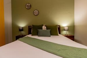 uma cama com paredes verdes e dois relógios na parede em Capitalia - Luxury Apartments - Temístocles 40 em Cidade do México