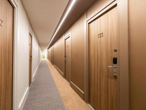 a long corridor with wooden doors and a long aisle at Novotel Nancy in Nancy