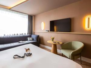 een hotelkamer met een bed, een bank en een tv bij Novotel Nancy in Nancy