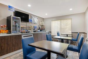 un comedor con 2 mesas y sillas azules en Best Western Courtesy Inn - Anaheim Park Hotel en Anaheim