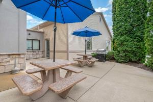 a patio with two picnic tables and a blue umbrella at Comfort Suites Lake Geneva East in Lake Geneva