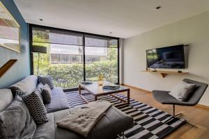 a living room with a couch and a table and a tv at Capitalia Temistocles Polanco in Mexico City