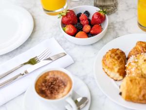 una mesa con platos de desayuno y un tazón de fresas en Mondrian Cannes, en Cannes