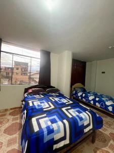a bedroom with two beds and a large window at Hostal Colonial in Cajamarca