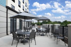 un patio con mesas, sillas y sombrillas en Fairfield by Marriott Inn & Suites Whitsett Greensboro East, en Whitsett