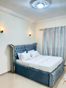 a blue bed in a room with a window at Appartement Rapha'ella Meublé in Yaoundé