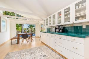 a kitchen with white cabinets and a table at Tranquil Marina Front Pool House Resort in Honolulu